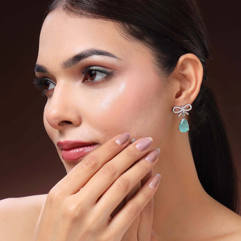 Rhodium Plated Silver Toned Bow Shaped Sea Green & White American Diamond Studded Drop Earrings
