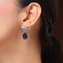 Rhodium Plated Silver Toned Bow Shaped Navy Blue & White American Diamond Studded Drop Earrings