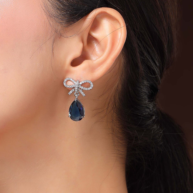 Rhodium Plated Silver Toned Bow Shaped Navy Blue & White American Diamond Studded Drop Earrings