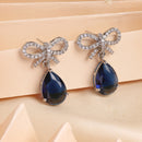Rhodium Plated Silver Toned Bow Shaped Navy Blue & White American Diamond Studded Drop Earrings